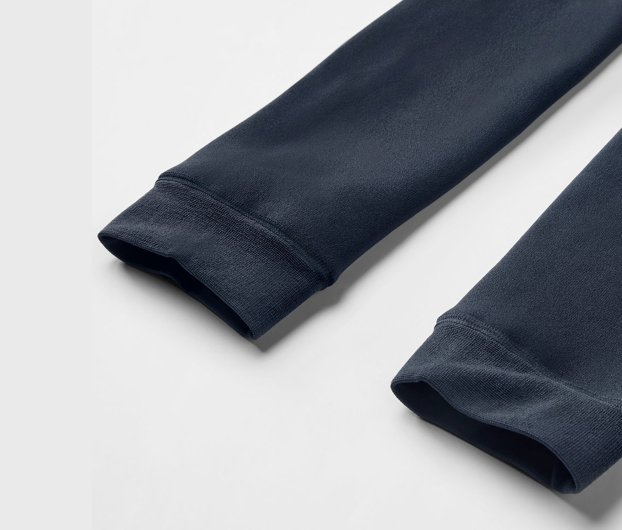 Gros plan sur les manches d'un sweat-shirt bleu marine avec poignets côtelés sur un fond blanc.