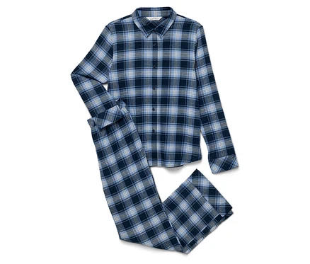 Un pyjama en flanelle à carreaux bleus, composé d'une chemise et d'un pantalon, est posé sur un fond blanc.
