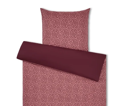 Literie à motif floral dans les tons rose et bordeaux.