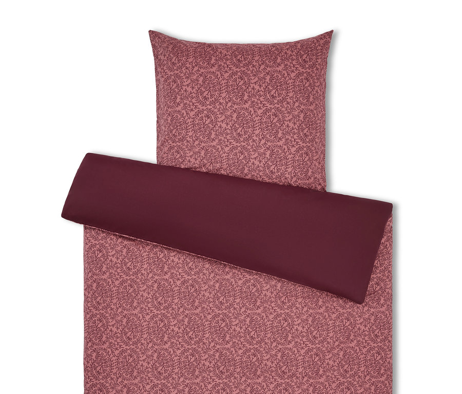 Literie à motif floral dans les tons rose et bordeaux.