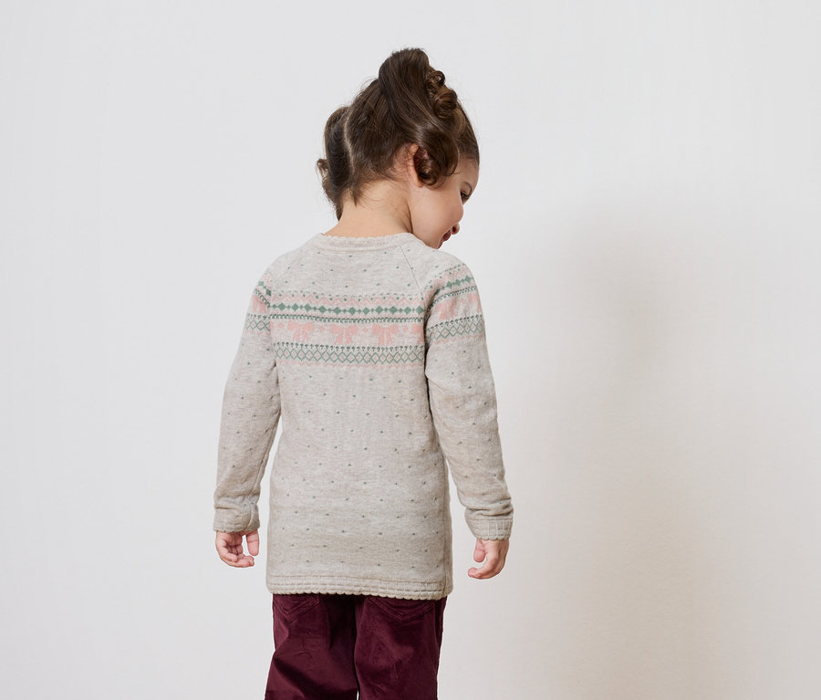 Fillette dos à la caméra portant un pull gris et un pantalon bordeaux.