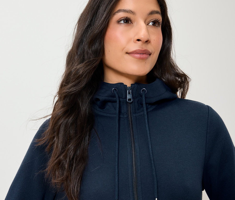 Une femme porte un sweat à capuche bleu marine zippé.