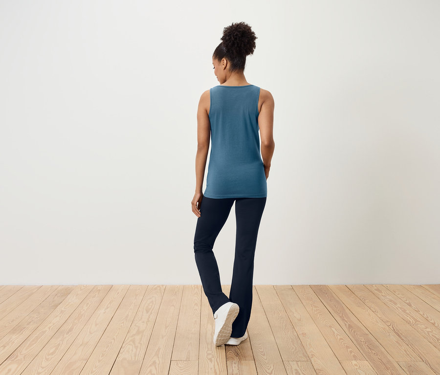 Une femme, vue de dos, porte un haut bleu et un pantalon bleu marine.