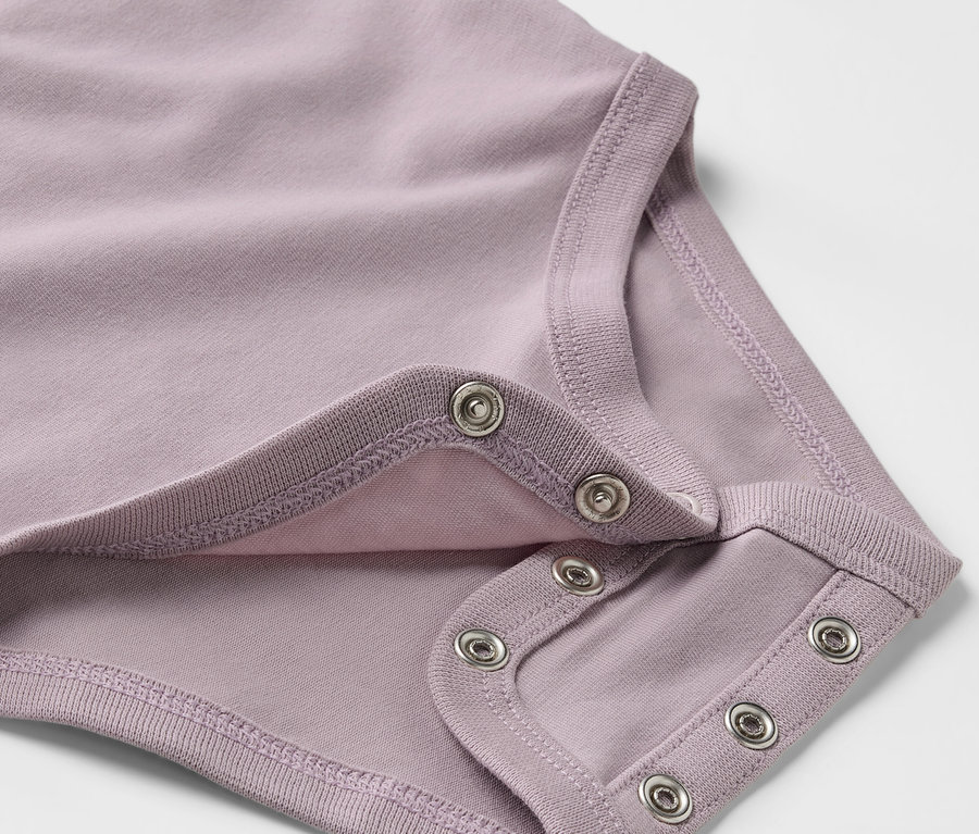 Gros plan sur un body pour bébé violet extensible avec des boutons-pression.