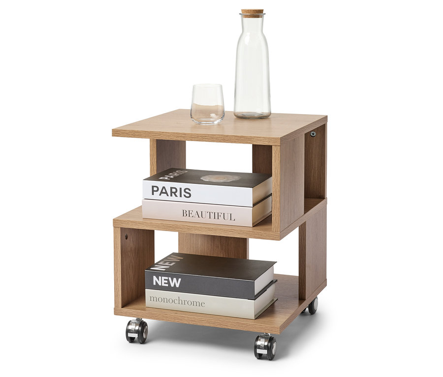 Sur un tabouret à roulettes marron clair se trouvent un verre, une bouteille avec un bouchon de liège et deux livres.