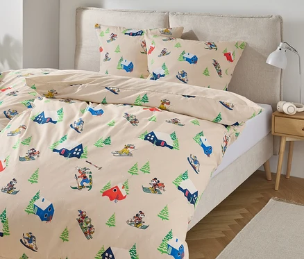 Linge de lit avec imprimé de skieurs et d'arbres sur un lit.