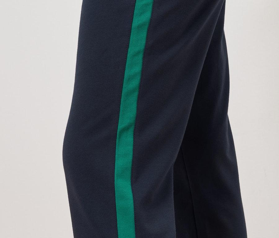 Détail d'un pantalon avec un fond bleu marine et une bande verte sur le côté.