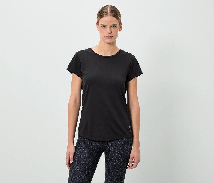 Une femme debout portant un t-shirt noir et un legging à motifs.