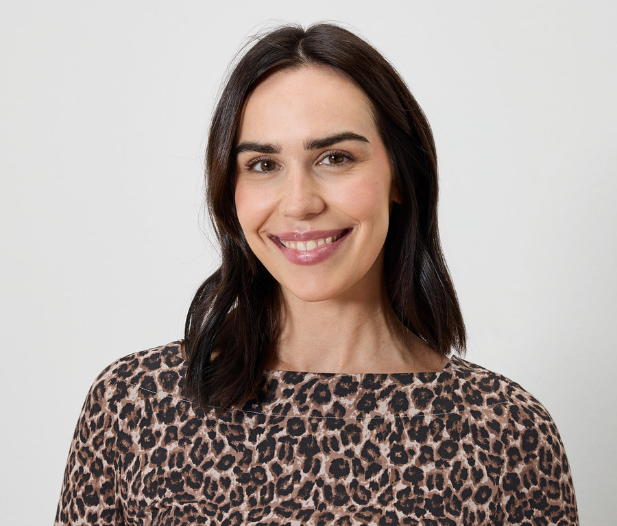 Portrait d'une femme souriante aux cheveux bruns portant un haut à motif léopard.