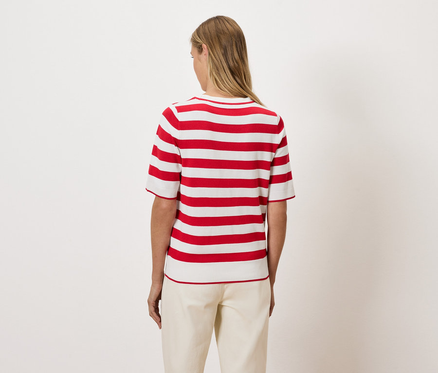 Une femme, vue de dos, porte un haut rayé rouge et blanc.