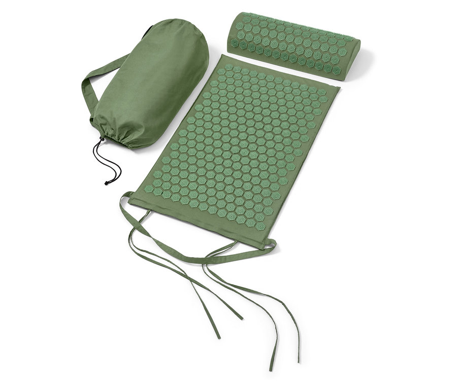 Un tapis d'acupression et un oreiller verts à côté d'un sac vert.