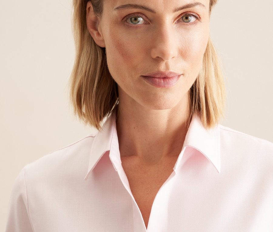 Portrait d'une femme blonde portant un chemisier en tulle rose Seidensticker.