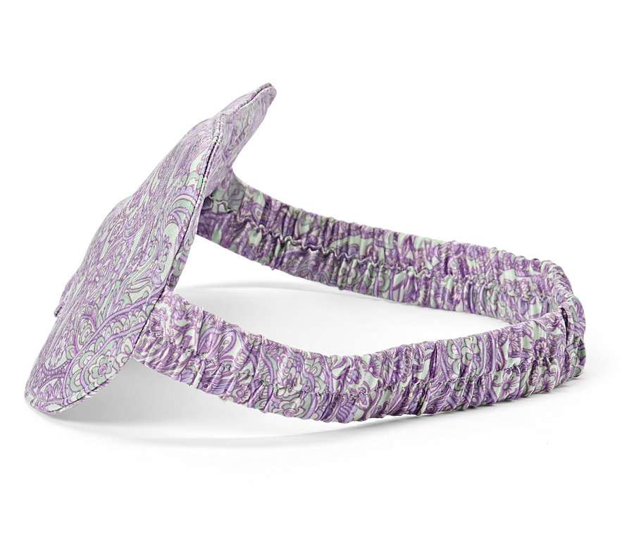 Gros plan d'un masque de sommeil violet à motifs avec un élastique sur fond blanc.