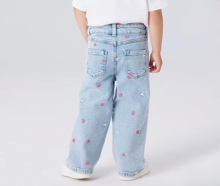 Vue arrière d'un enfant portant un jean bleu clair avec des imprimés de cœurs roses et blancs.
