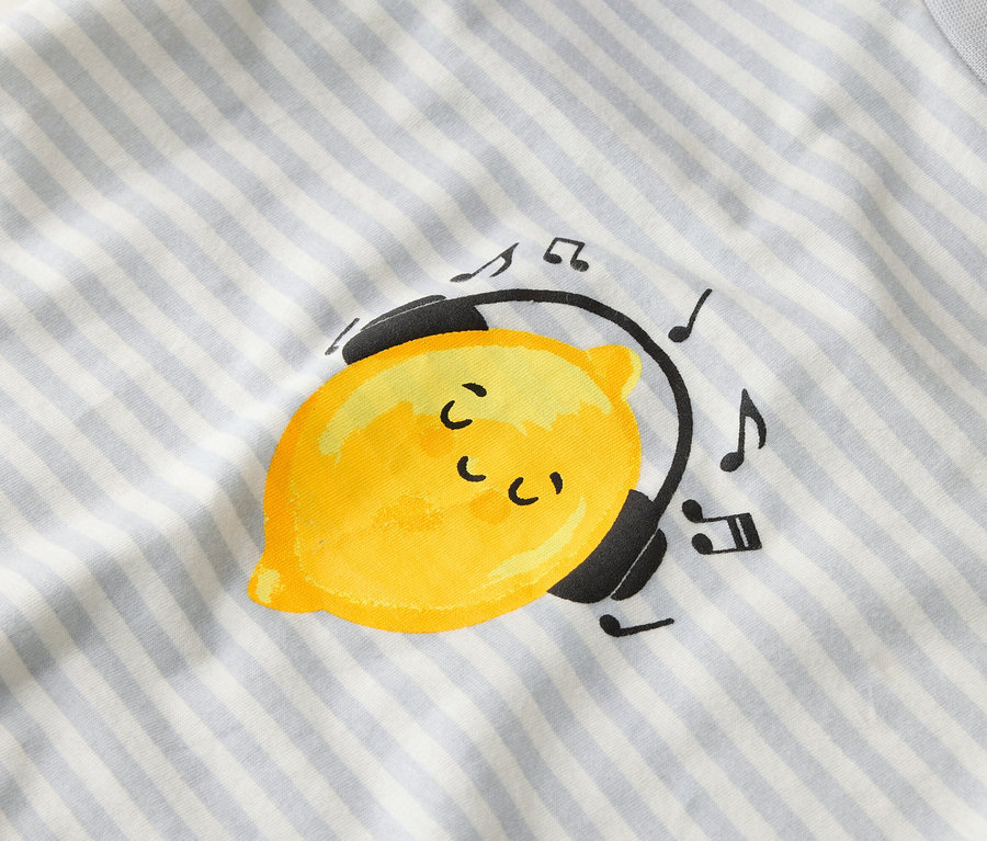 Sur un tissu rayé, un citron jaune porte un casque audio avec des notes de musique.