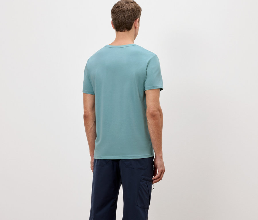 Vue arrière d'un homme portant un t-shirt bleu clair et un pantalon bleu foncé sur un fond blanc.