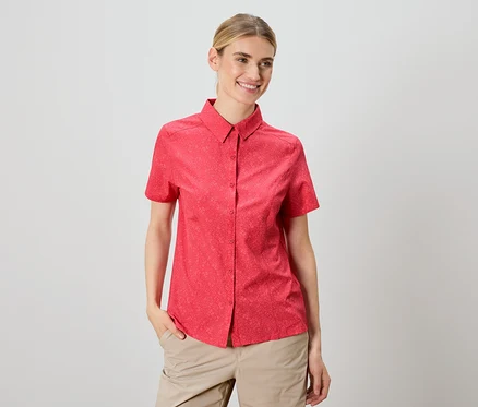Une femme porte une chemise rouge à manches courtes et un pantalon beige.
