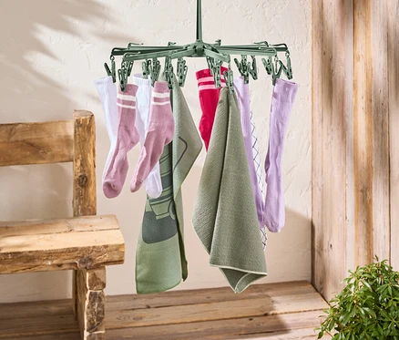 Un étendoir à linge vert est suspendu à une corde à linge rouge. Des chaussettes et des serviettes sont suspendues à l'étendoir à linge.