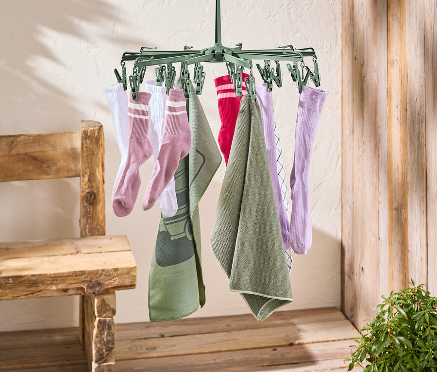Un étendoir à linge vert est suspendu à une corde à linge rouge. Des chaussettes et des serviettes sont suspendues à l'étendoir à linge.