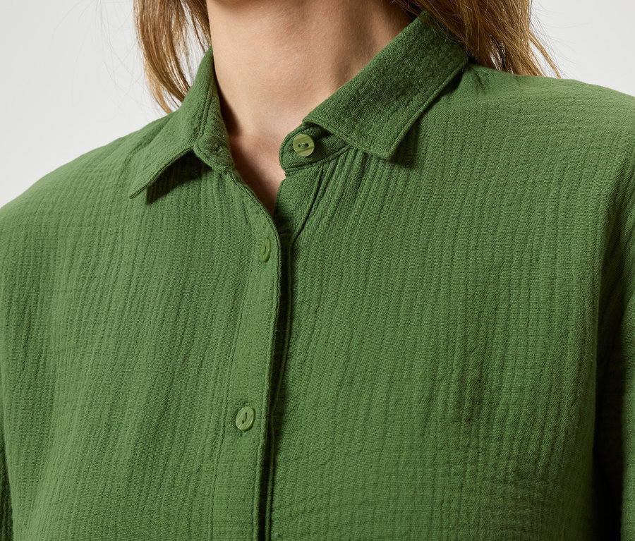 Gros plan d'une personne portant une chemise verte boutonnée.