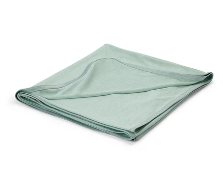 Couverture de bébé vert clair pliée sur fond blanc.