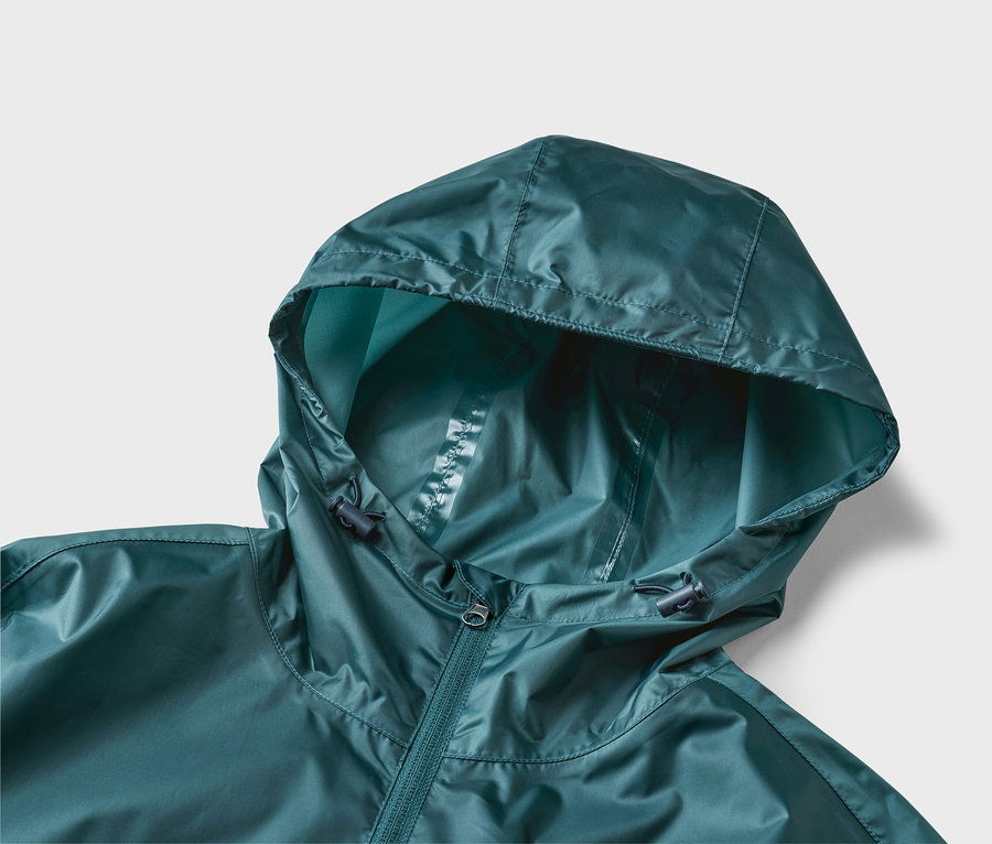 Gros plan d'un imperméable vert foncé avec capuche et fermeture éclair sur fond neutre.