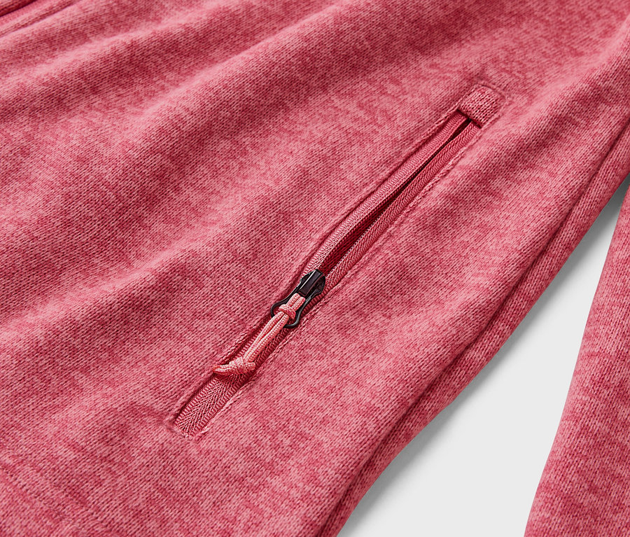 Gros plan d'une veste polaire rouge avec une poche zippée.