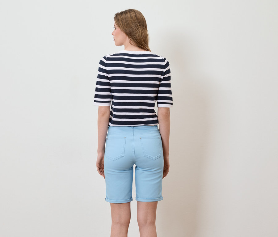 Vue arrière d'une femme aux longs cheveux blonds portant un t-shirt rayé marine et blanc à manches courtes et un short bleu clair.