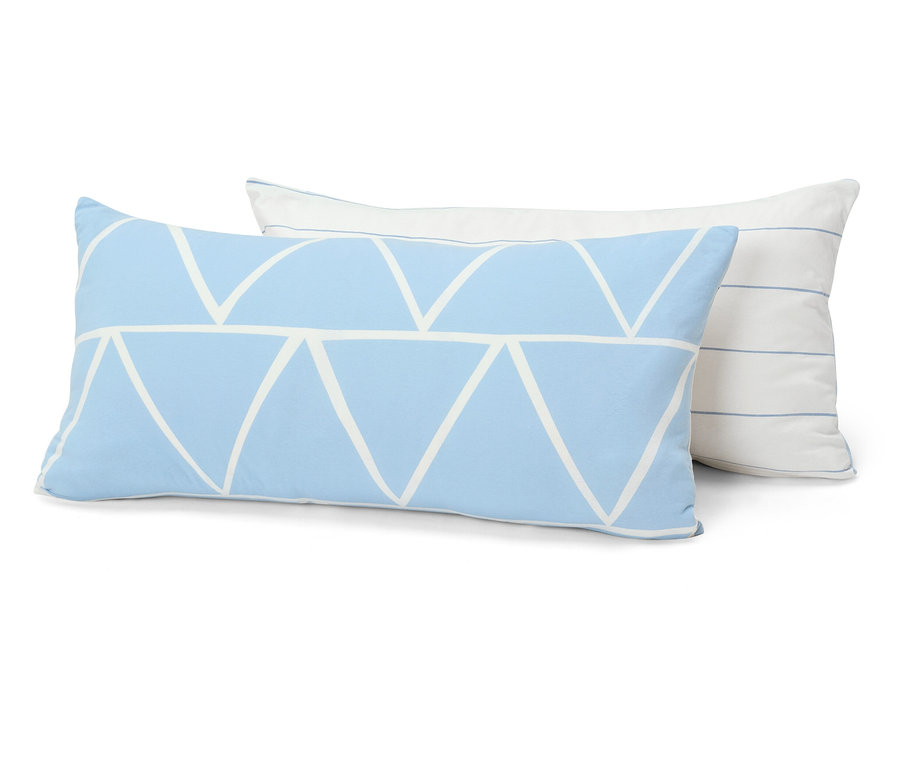 Deux coussins décoratifs sont superposés. Le coussin avant est bleu clair avec un motif triangulaire blanc. Le coussin arrière est blanc avec de fines rayures bleues.