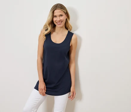 Une femme porte un débardeur bleu marine et un jean blanc.