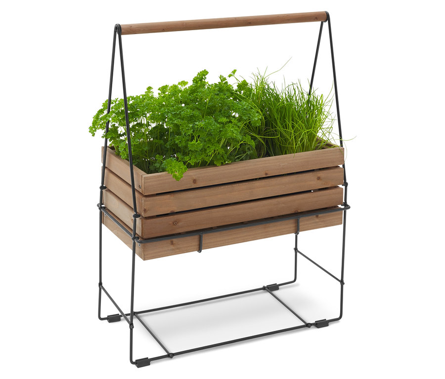 Jardinière en bois contenant du persil et de la ciboulette, sur un cadre métallique noir avec une poignée en bois.