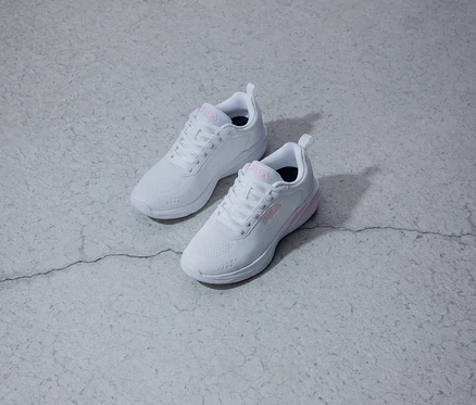 Deux baskets blanches Fila avec un logo rose sont posées sur un fond gris.