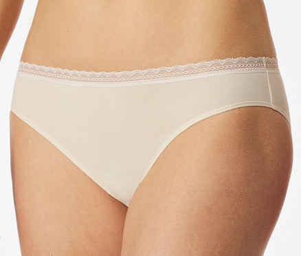 Une personne porte un slip Rio SCHIESSER beige avec une délicate bordure en dentelle blanche à la taille.