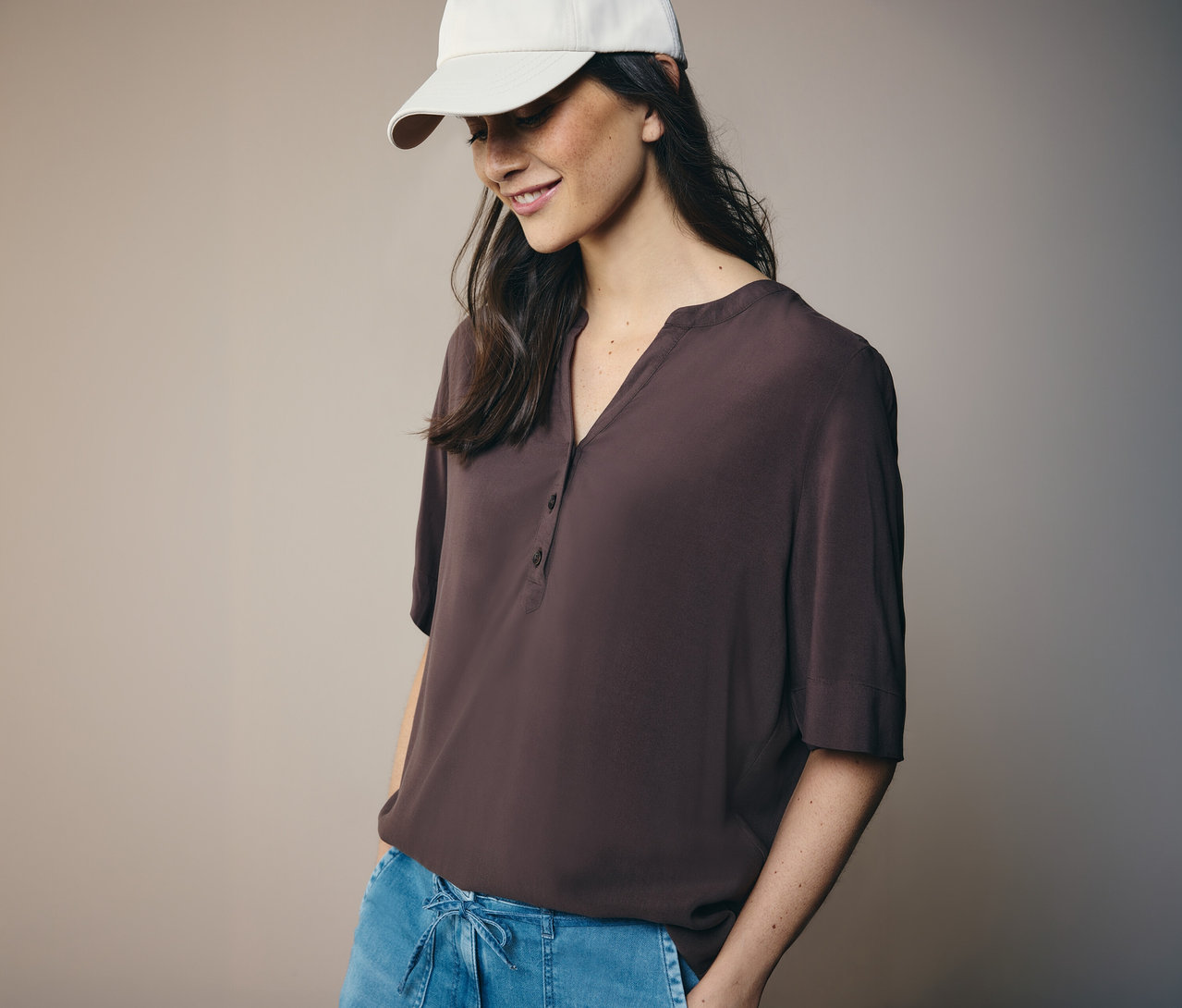 Femme portant une casquette blanche et un chemisier tunique CECIL marron.