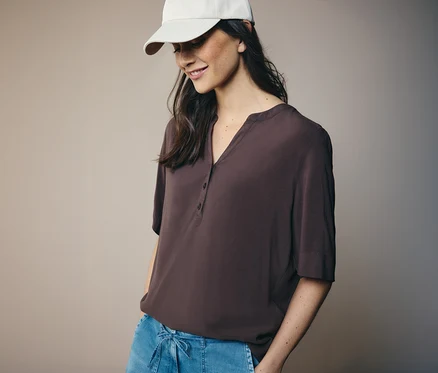 Femme portant une casquette blanche et un chemisier tunique CECIL marron.