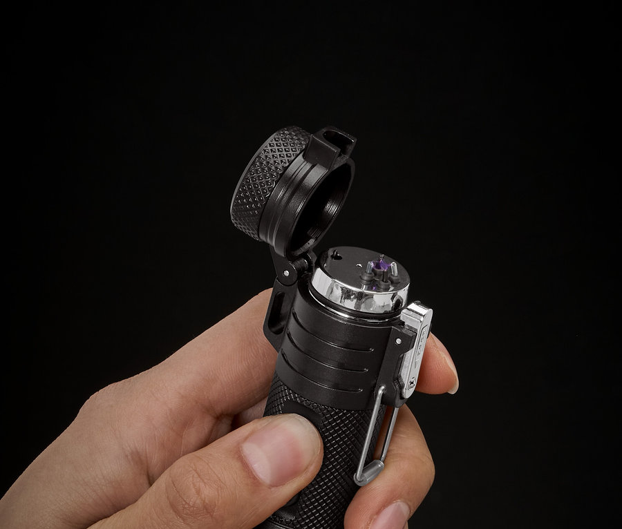 Une main tient un briquet noir sur un fond noir.