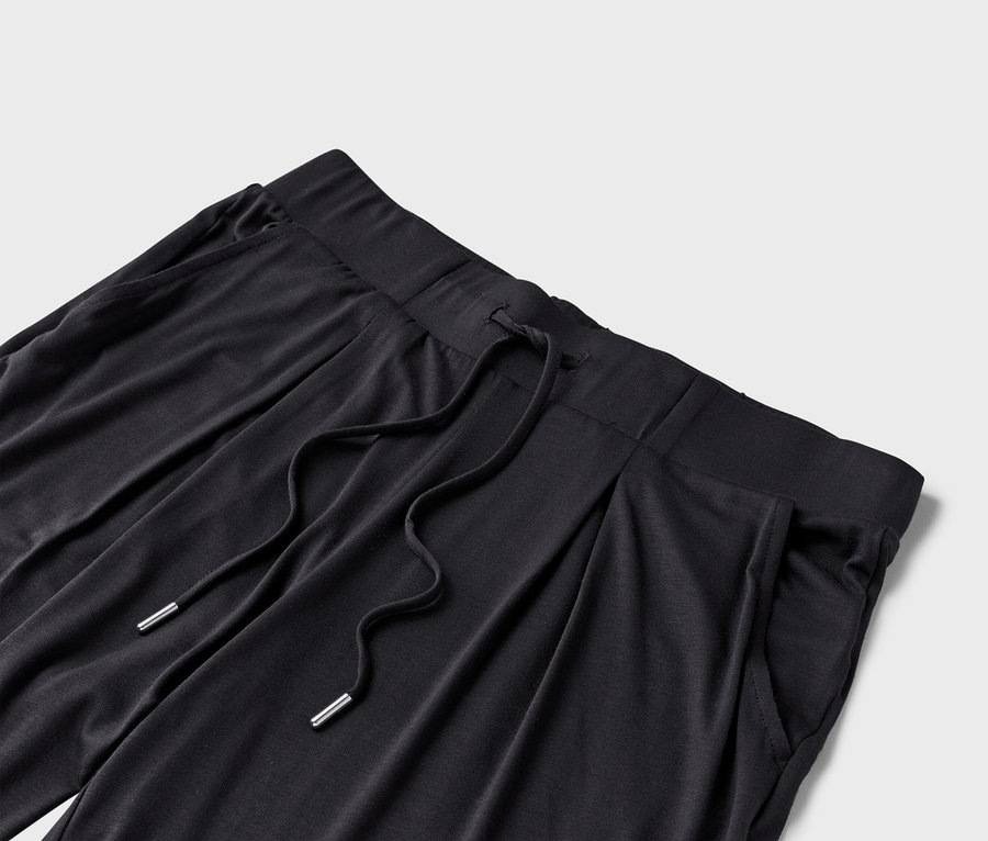 Gros plan sur un pantalon en tissu noir avec cordon de serrage et poches.