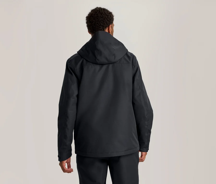 Personne vue de dos, portant une veste à capuche foncée et un pantalon foncé.