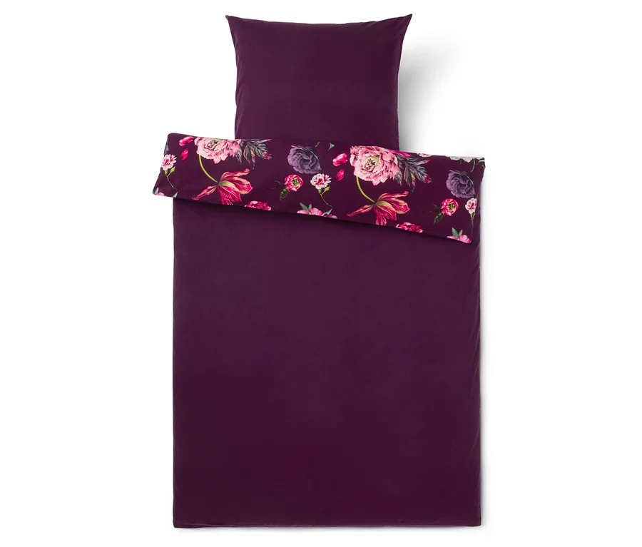 Parure de lit violet foncé avec une taie d'oreiller, la housse de couette est repliée, révélant un motif floral de fleurs roses et violettes.