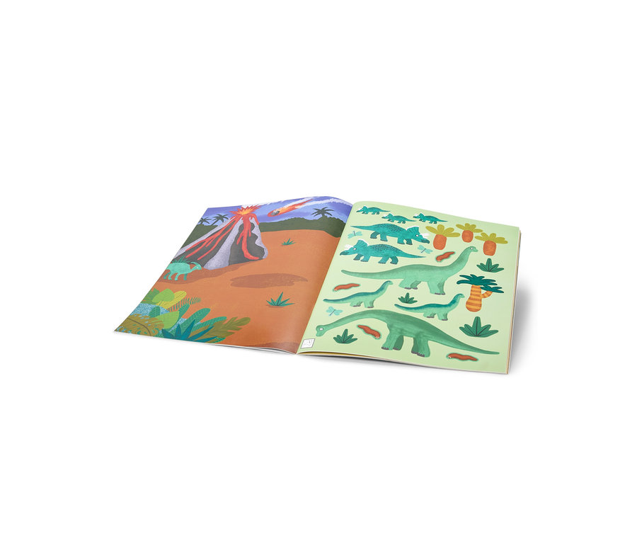 Un livre ouvert montre sur la page de gauche un paysage volcanique en éruption avec un météore dans le ciel, et sur la page de droite divers dinosaures verts et des palmiers.