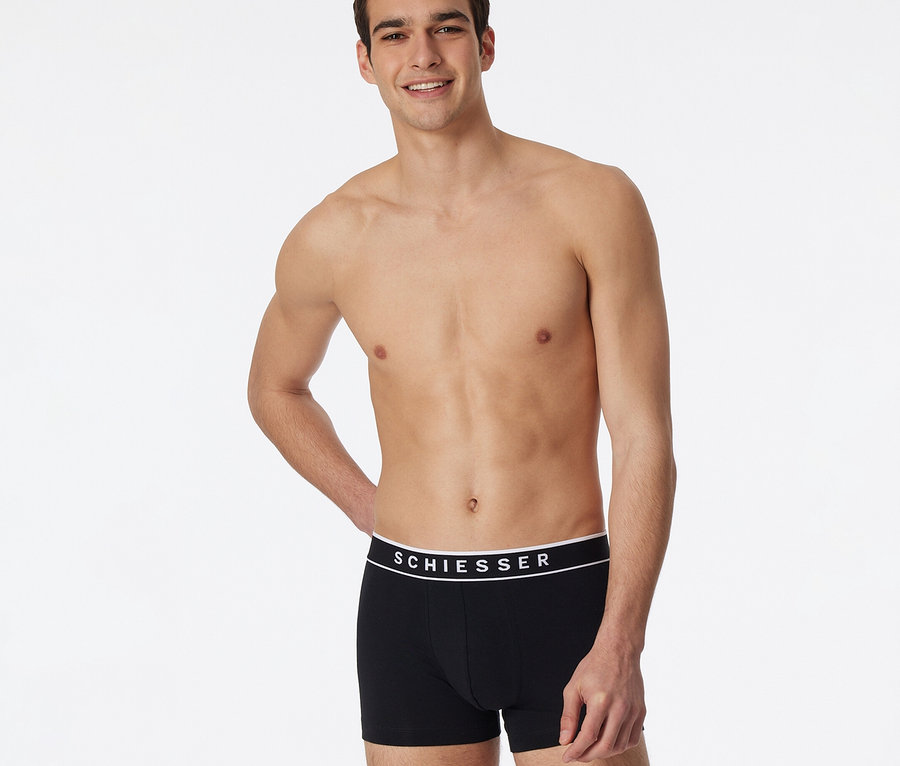 Homme souriant portant un short SCHIESSER noir avec une ceinture blanche, faisant partie d'un lot de 3.