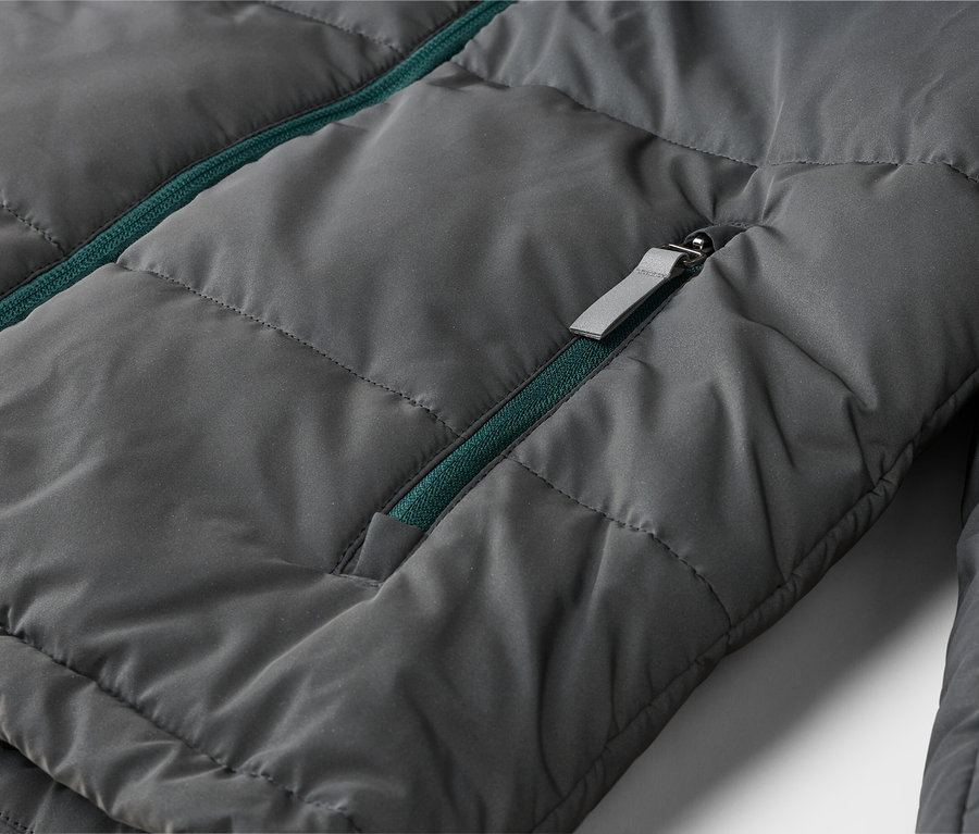 Veste matelassée gris foncé avec une fermeture éclair verte et une tirette grise.