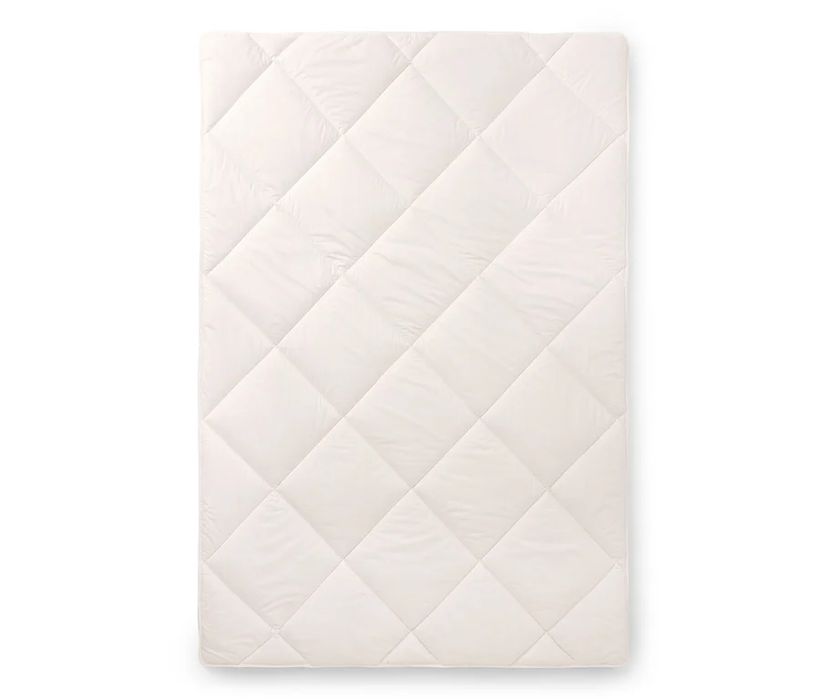 Un protège-matelas matelassé rectangulaire de couleur crème avec un motif en losanges.