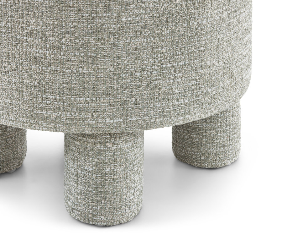 Gros plan d'un tabouret rembourré vert clair avec un tissu texturé et moucheté et trois pieds cylindriques visibles.