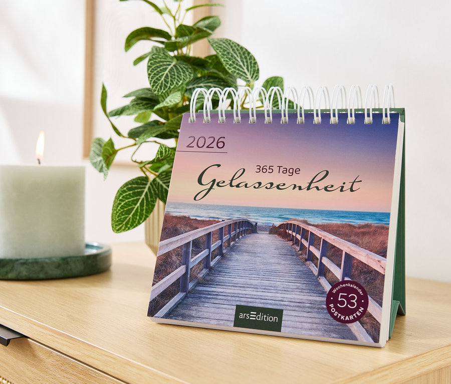 Sur une commode se trouvent un calendrier avec l'inscription Gelassenheit, une bougie et une plante.