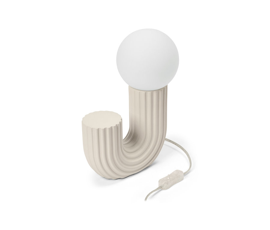 Lampe de table crème en forme de J avec une texture côtelée et une ampoule ronde blanche, avec un câble et un interrupteur.