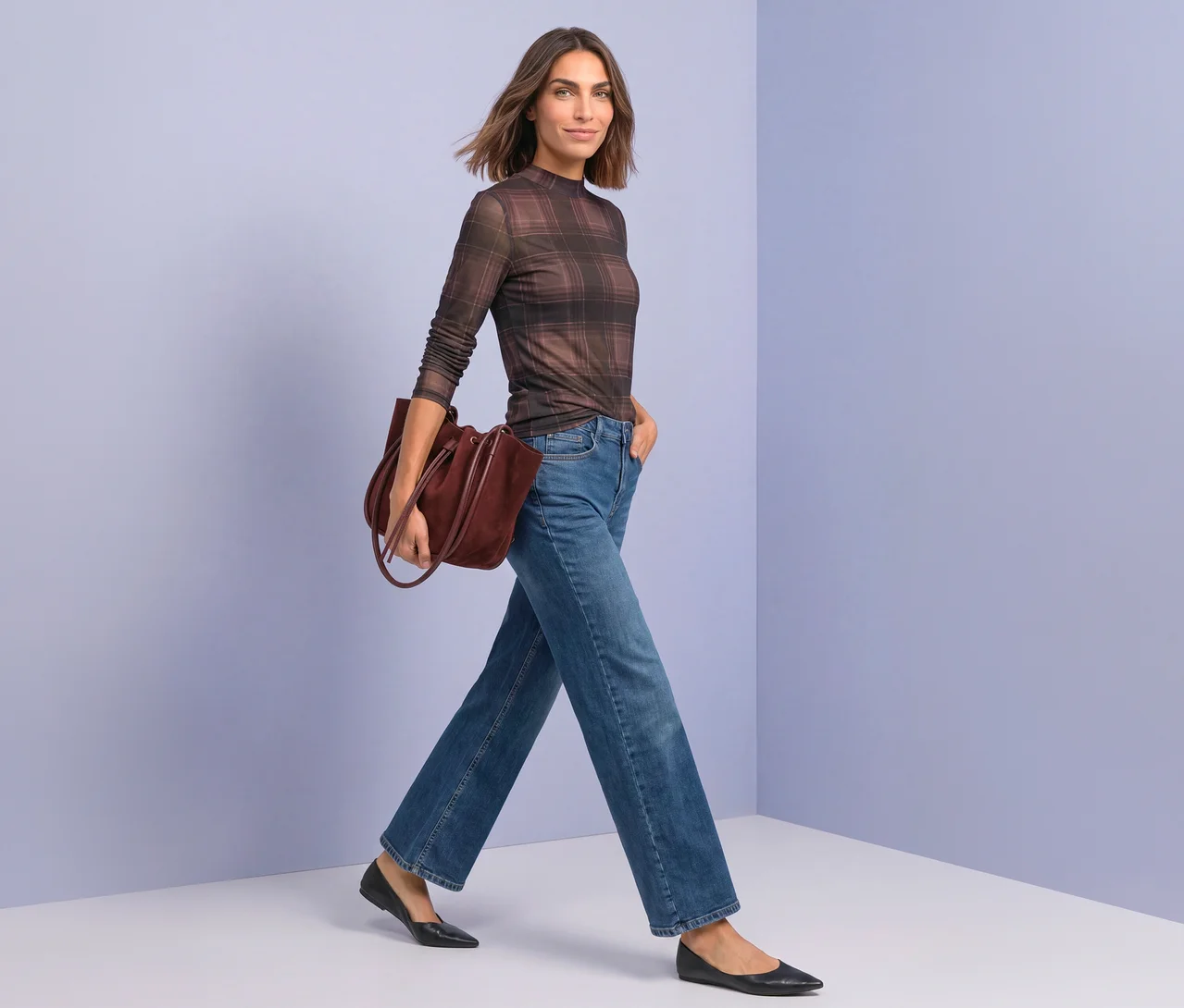 Femme marchant, portant un T-shirt en maille Street One à carreaux marron, un jean large bleu, des ballerines noires et un sac cabas bordeaux.