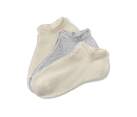 Gros plan de trois paires de socquettes pour enfants beiges et gris clair.
