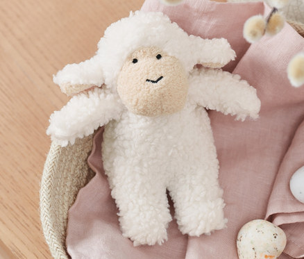 Un mouton avec son repose dans un panier avec des chatons et des œufs peints.