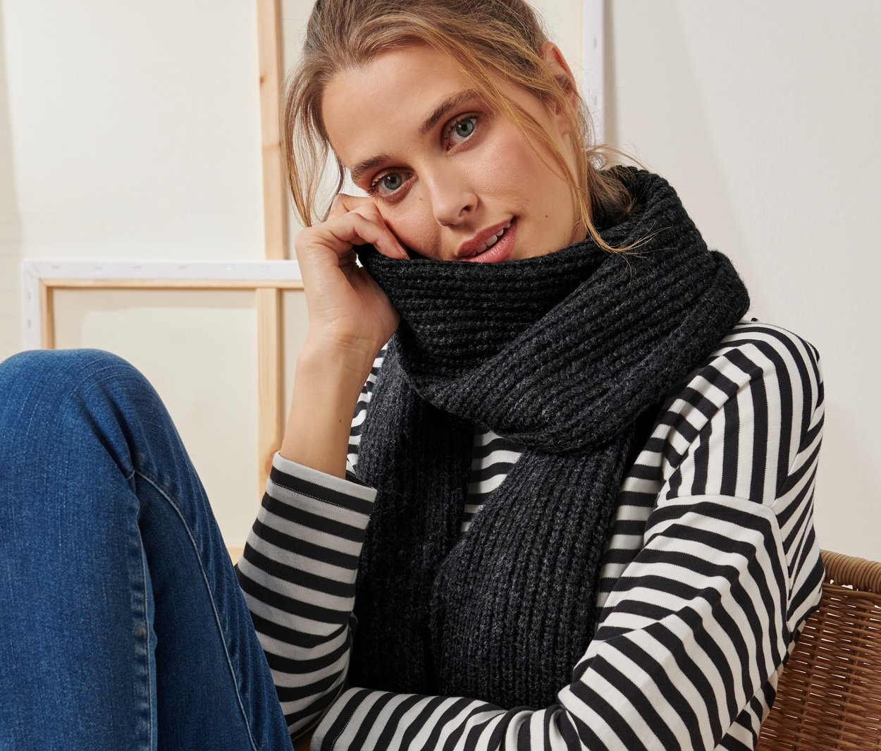 Une femme est assise sur une chaise et porte une écharpe en maille anthracite.